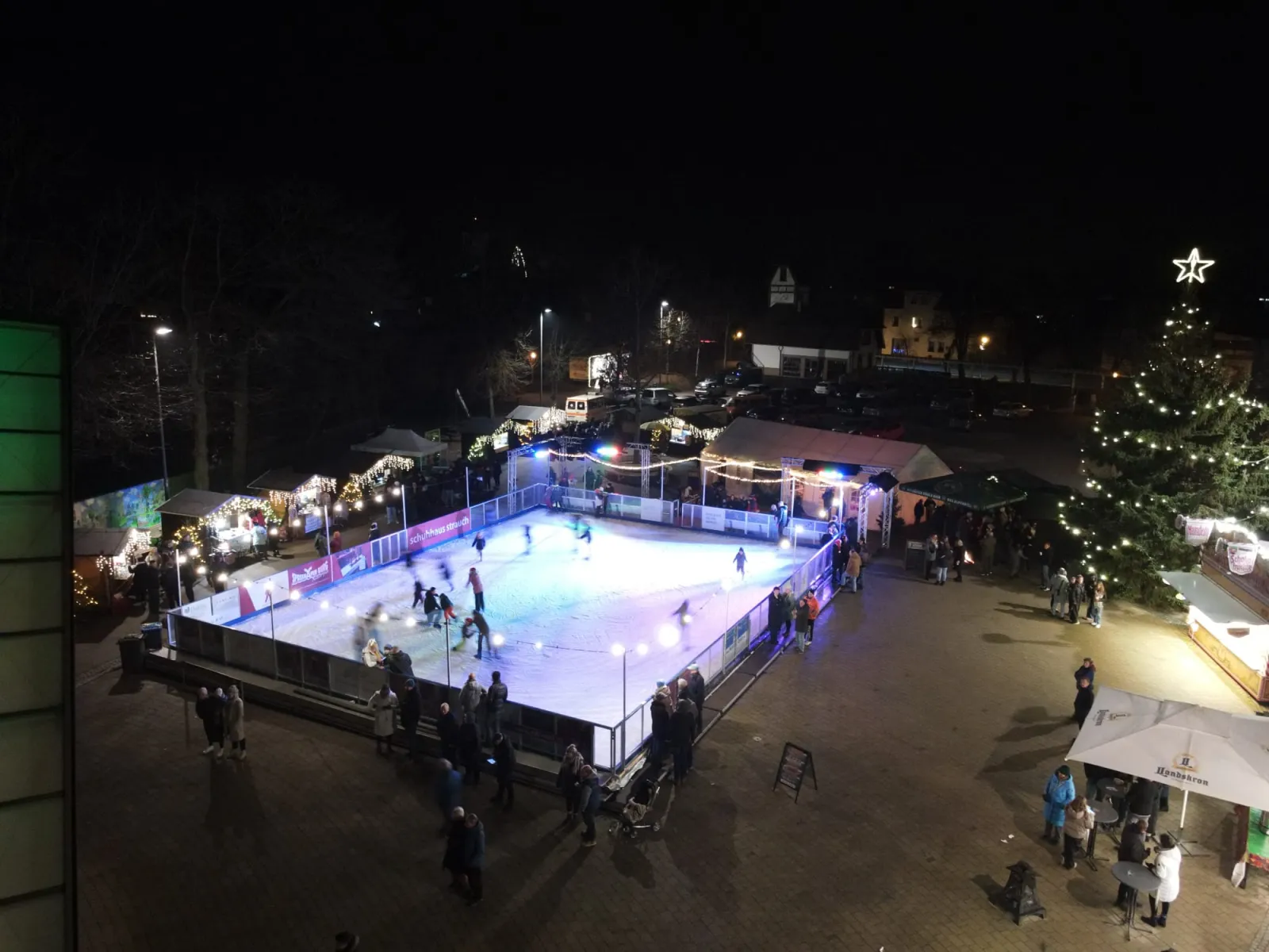 The Eisbahn Burg seen from above at night, the lit ice surface among the market stalls and a Christmas tree at the Festplatz am Hafen — Eisbahn Burg (Spreewald)