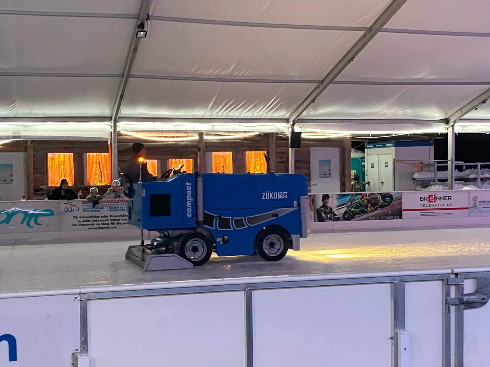 The covered ice at Eisbahn Schüpfen with the ice resurfacer and the restaurant cabin behind — Eisbahn Schüpfen