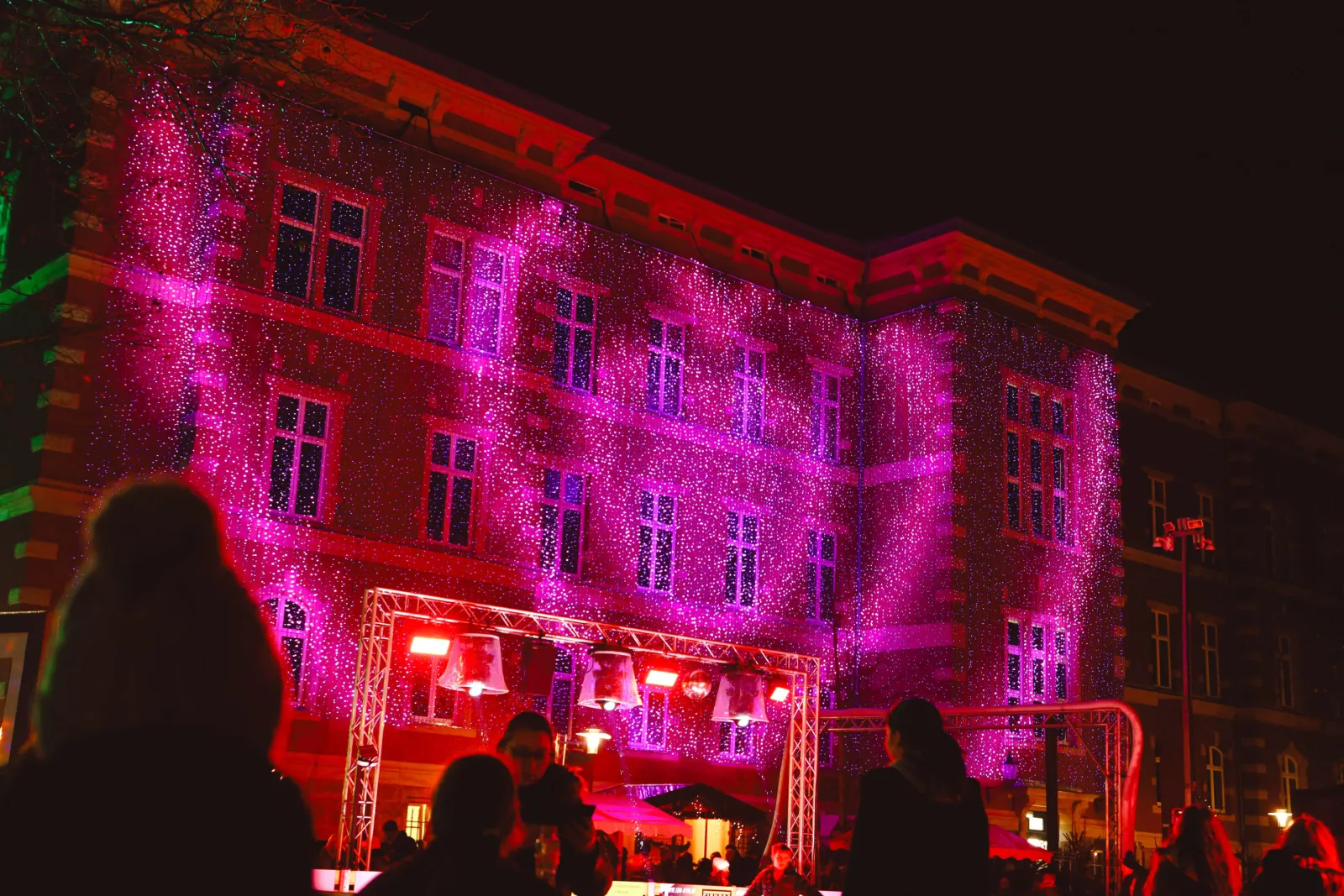 Das Jacobson-Haus am Jacobsonplatz mit pinkfarbener Lichtinstallation neben der Eisbahn während des Lichterzaubers. – Eisbahn Seesener Lichterzauber