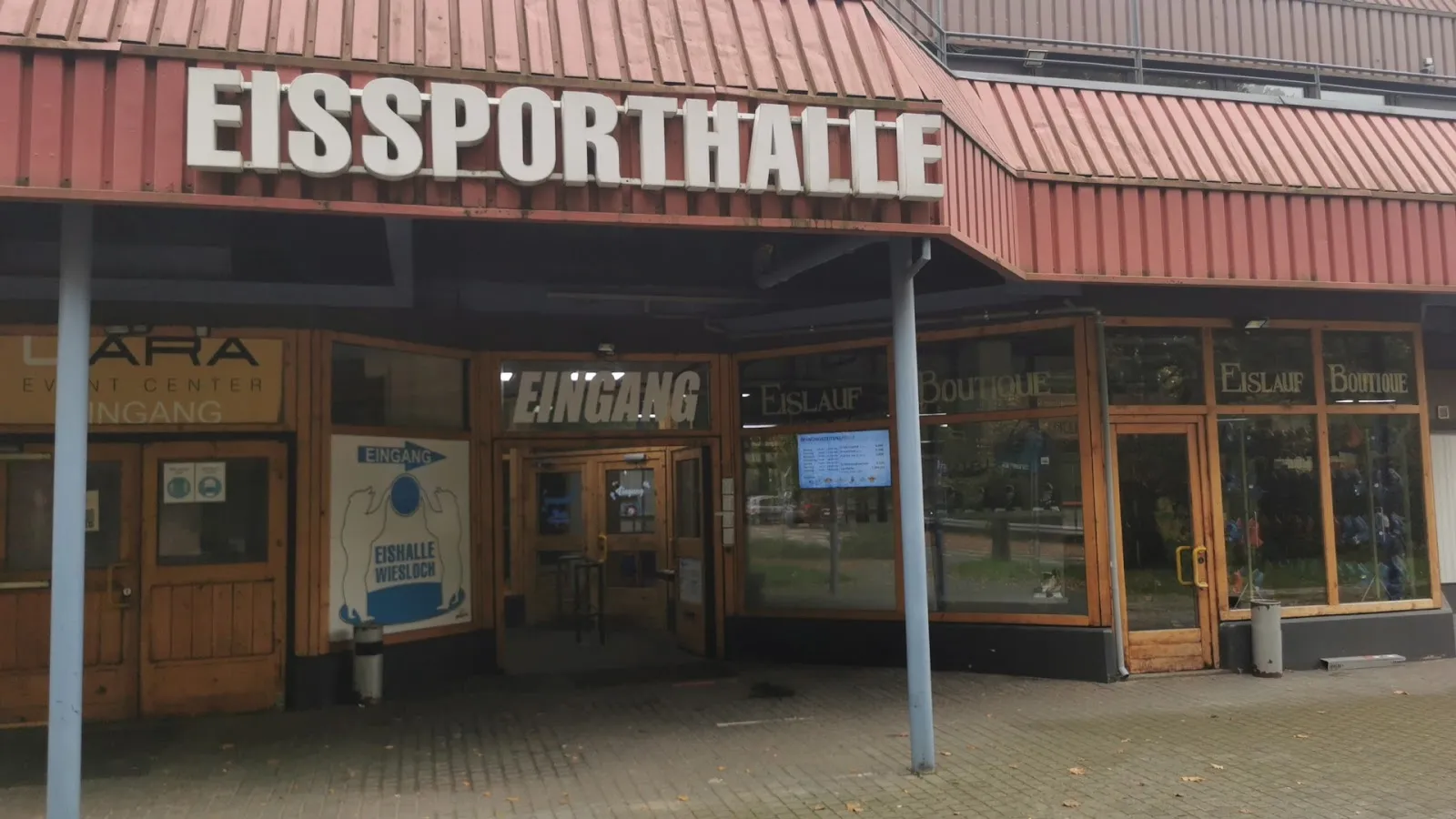 The timber and red-roofed entrance of the Eissporthalle in Wiesloch, with the name in large letters and the Eingang signs over the doors — Eishalle Wiesloch