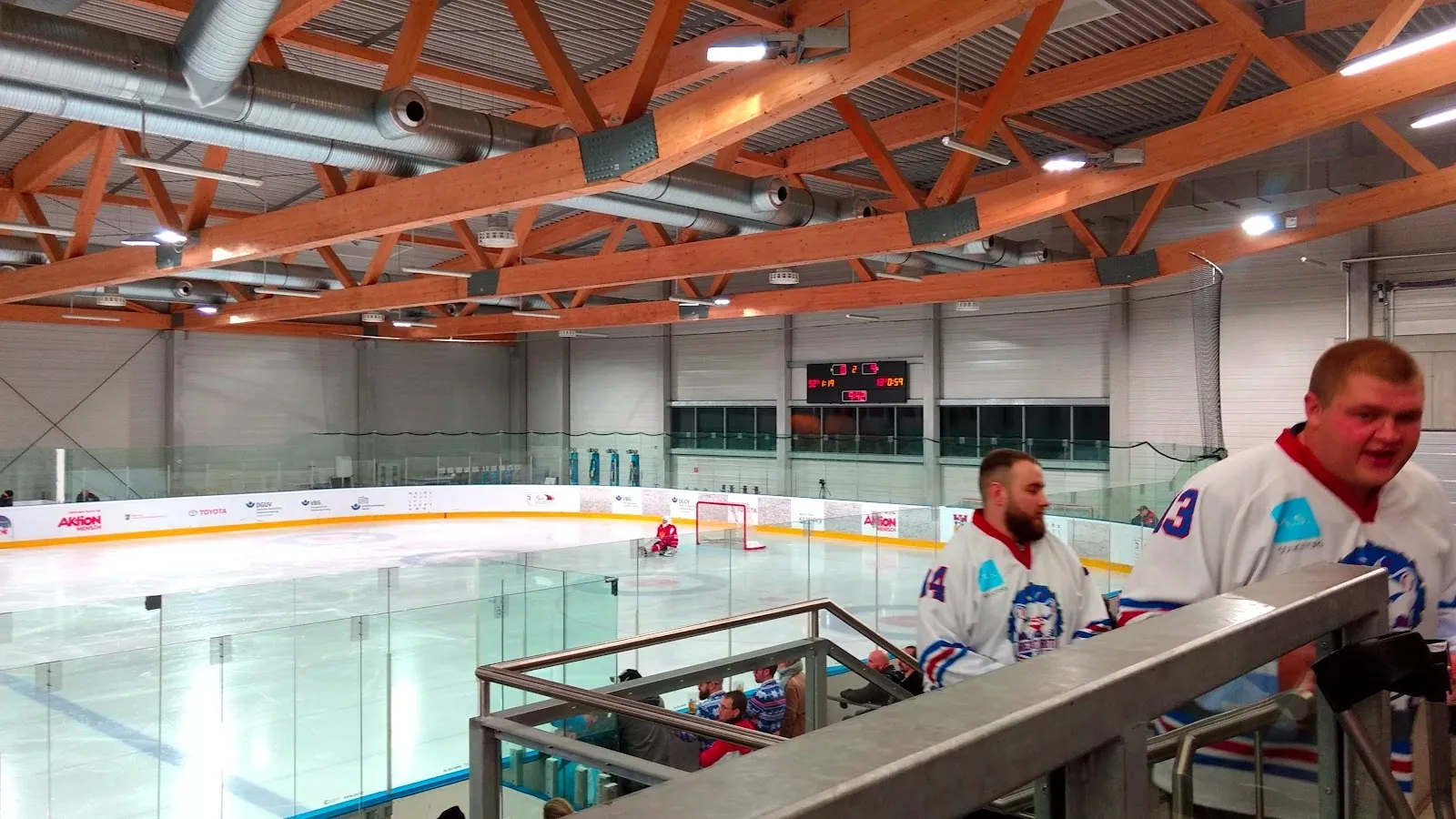 The ice of the Eissporthalle Charlottenburg in Berlin seen across the rink with the glazed wall, the timber roof and the stand at the side. — Eissporthalle Charlottenburg (PO9)