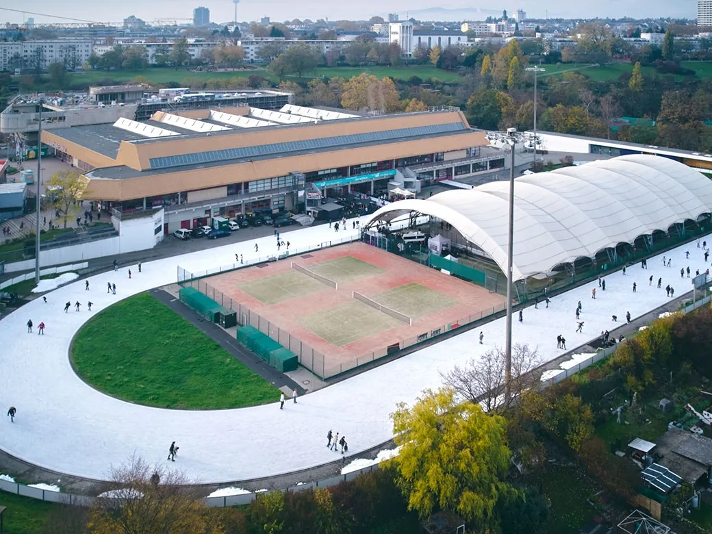 Luftaufnahme der Eissporthalle Frankfurt: die Halle mit ihrem Holzdach neben dem Freiluft-Oval und dem Eisfeld mit weißem Dach – Eissporthalle Frankfurt