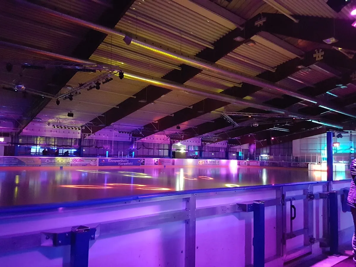 Die Eisfläche und das Holzdach der Eissporthalle Harsefeld unter farbigem Licht. – Eissporthalle Harsefeld