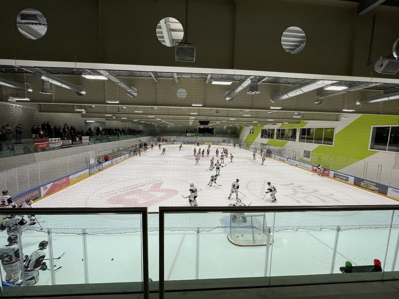 A hockey game in play at the Lerchenfeld ice sports centre in St. Gallen, players across the ice seen from the glass-fronted gallery. — Eissportzentrum Lerchenfeld