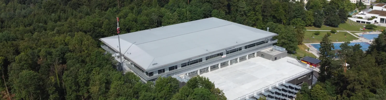 Aerial view of the Eissportzentrum Schluefweg in the Kloten forest, with the flat-roofed Schluefweg HALLE beside the SWISS Arena — Eissportzentrum Schluefweg