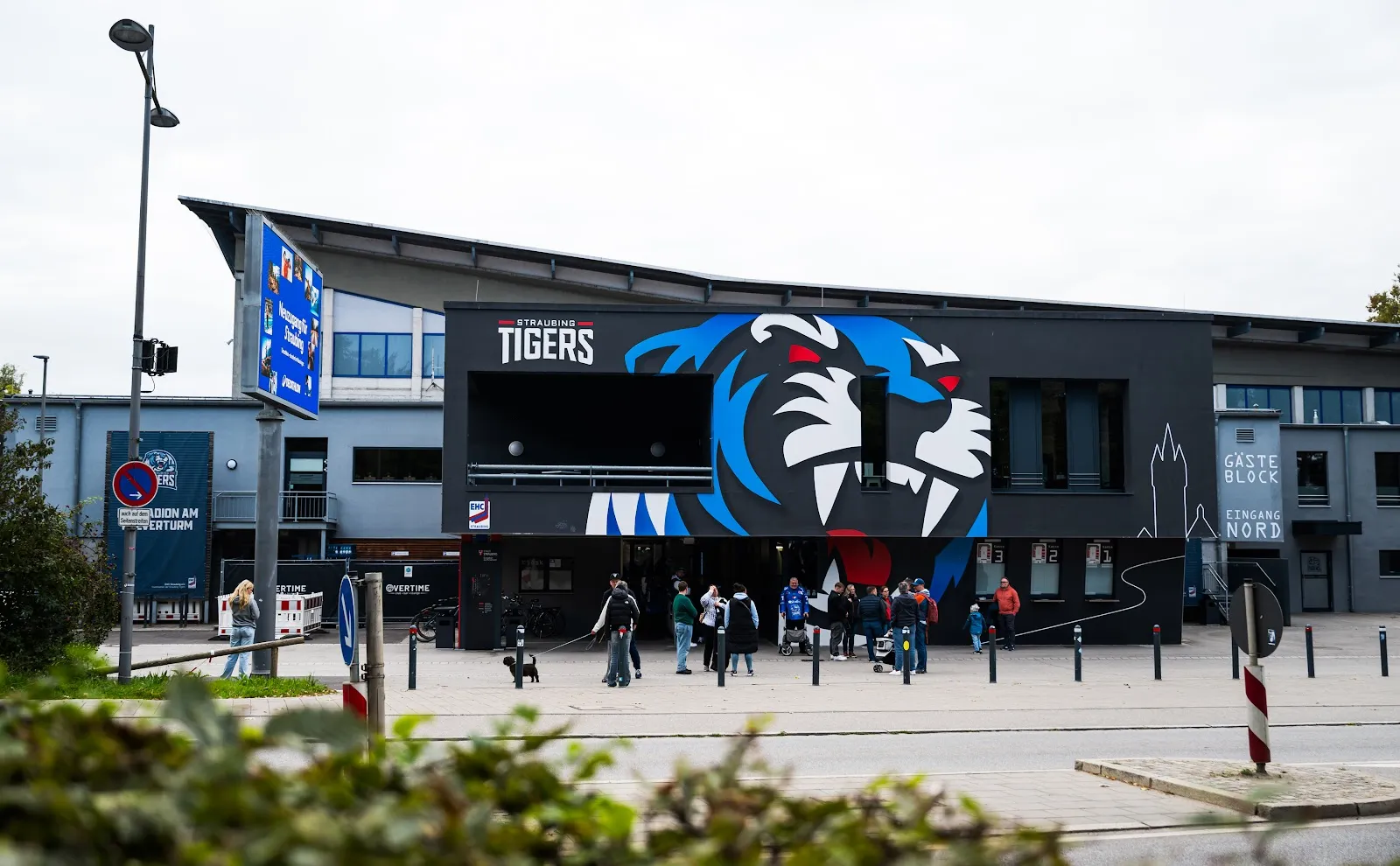 The stadium's dark façade with the large Straubing Tigers tiger-head graphic above the entrance plaza. — Eisstadion am Pulverturm