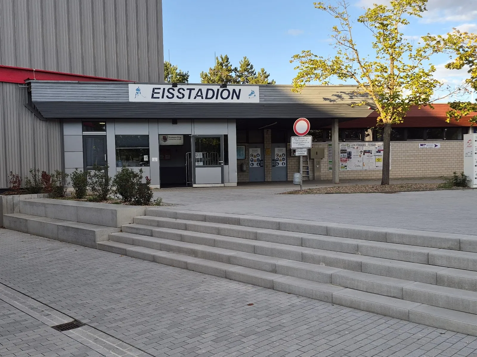 The entrance front of the Eisstadion Höchstadt with its sign above the doors and the steps up to the building. — Eisstadion Höchstadt an der Aisch