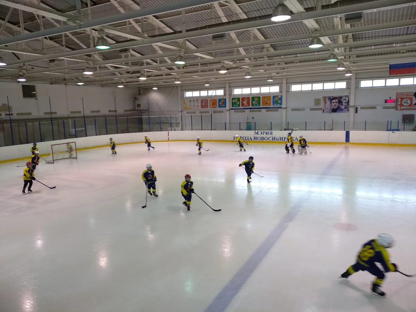 Young hockey players training on the ice of the Energiya ice complex in Novosibirsk, with the boards and a covered roof above — Energiya Ice Rink Novosibirsk
