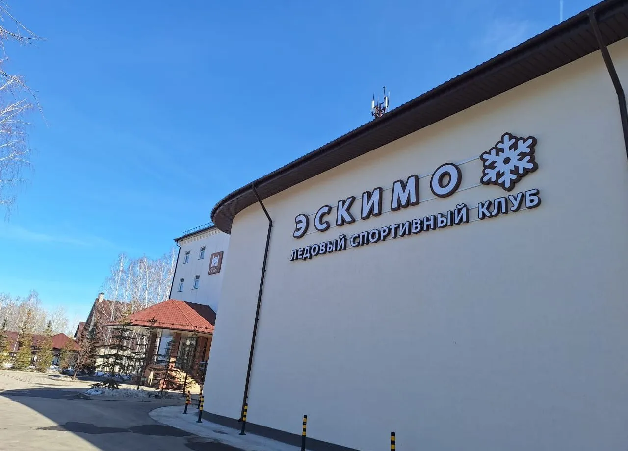 The Eskimo ice sports club building in Tyumen, a pale wall with the Eskimo logo and a snowflake under a clear blue sky — Eskimo Ice Arena Tyumen