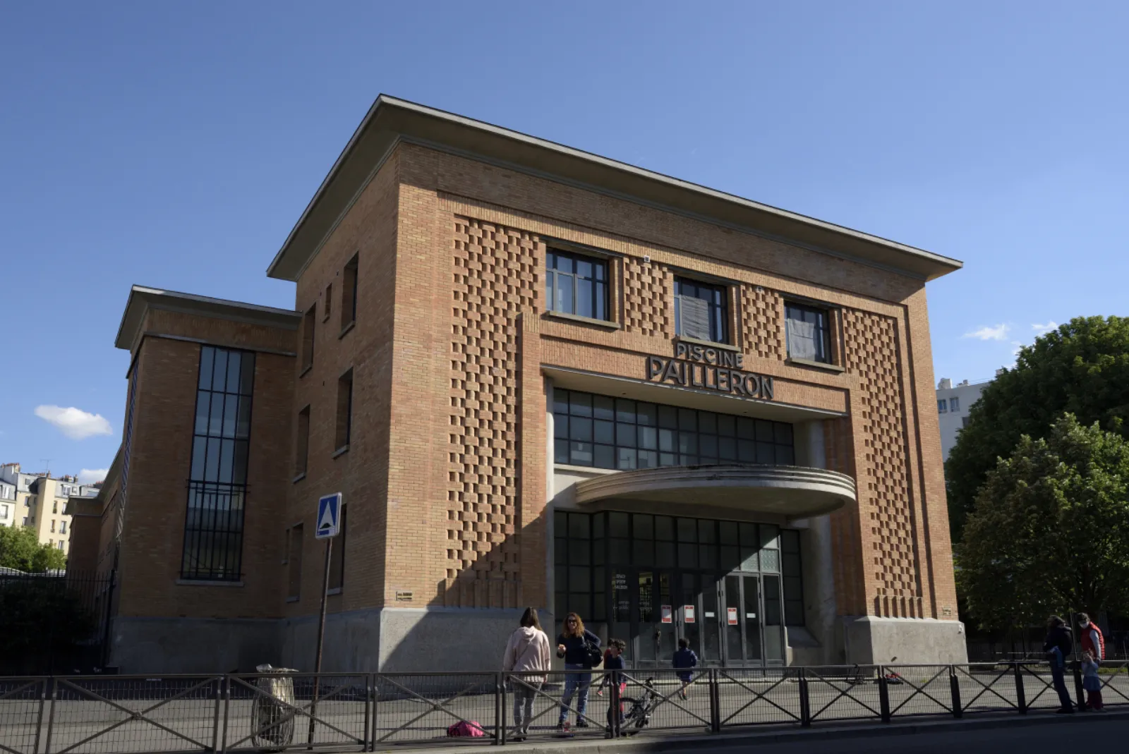 The red-brick street facade of the Espace Sportif Pailleron with its patterned brickwork, tall windows and the PAILLERON lettering above the entrance canopy. — Patinoire Pailleron