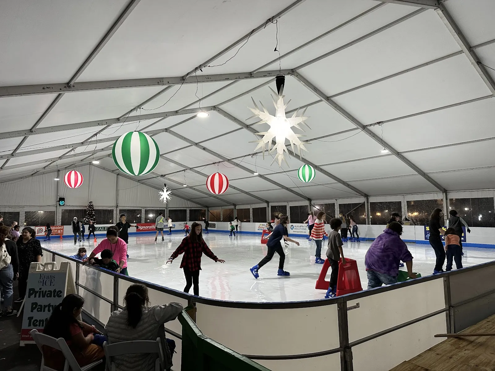 Skaters on the covered rink at Evans on Ice, with its holiday decorations — Evans on Ice