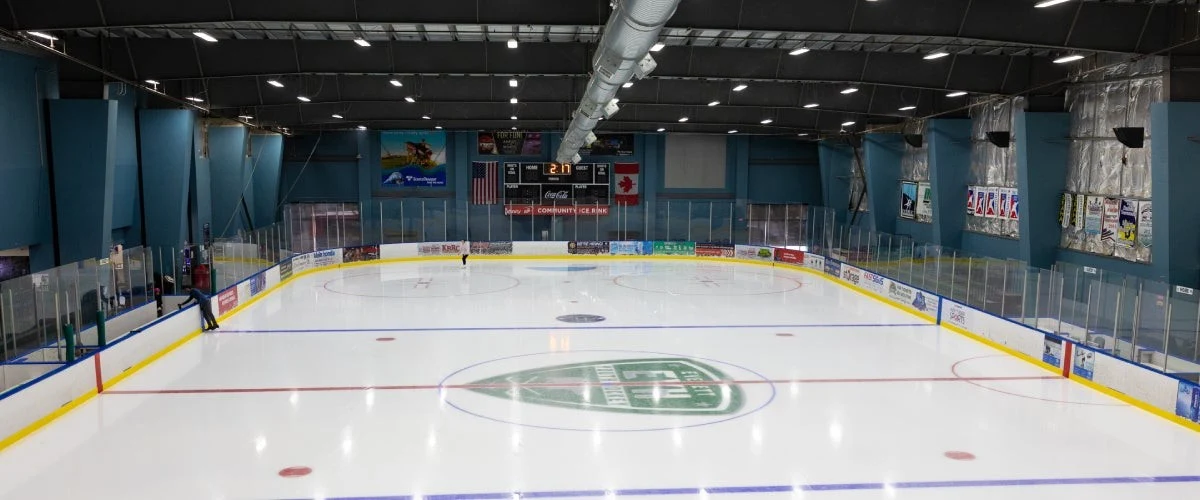 A full-length view of Everett's community ice sheet with its center-ice logo and blue wall panels. — Everett Community Ice Rink