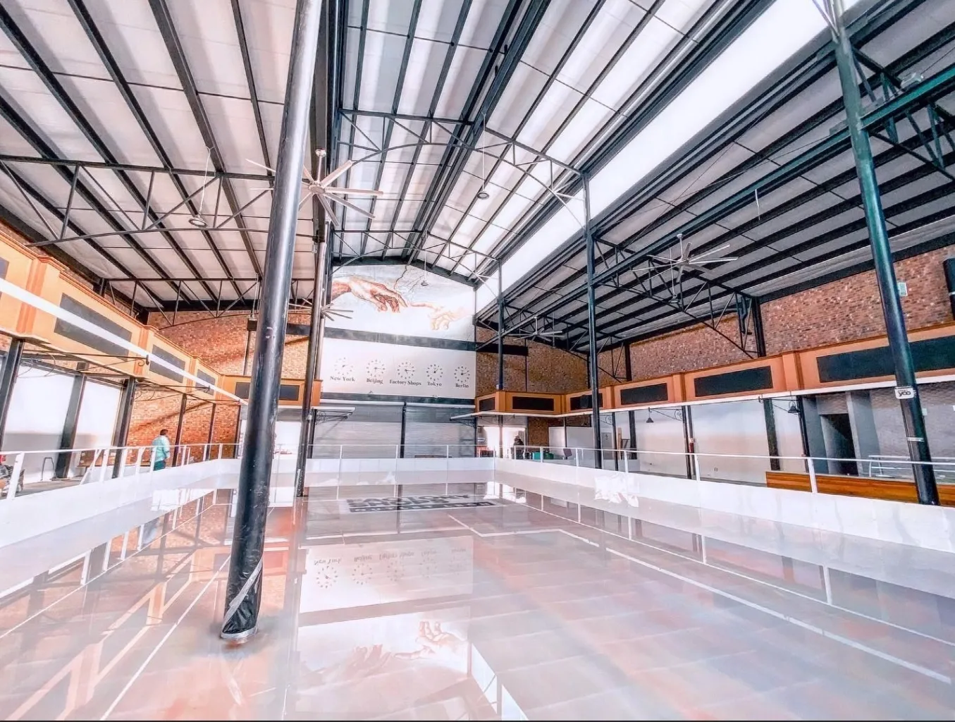 La pista vacía dentro de la nave de Factory Shops en una vista gran angular, bajo la estructura de acero del techo con tragaluces y paredes de ladrillo. — Factory on Ice