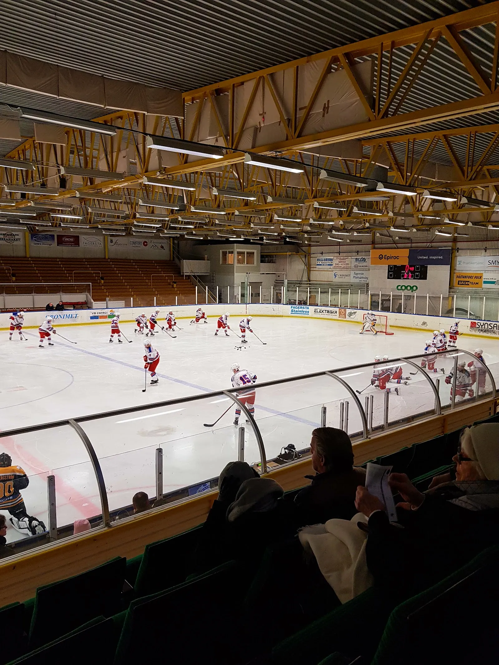 En hockeymatch på isen i Fagerlidens ishall sedd från läktaren under taket av trä – Fagerlidens ishall