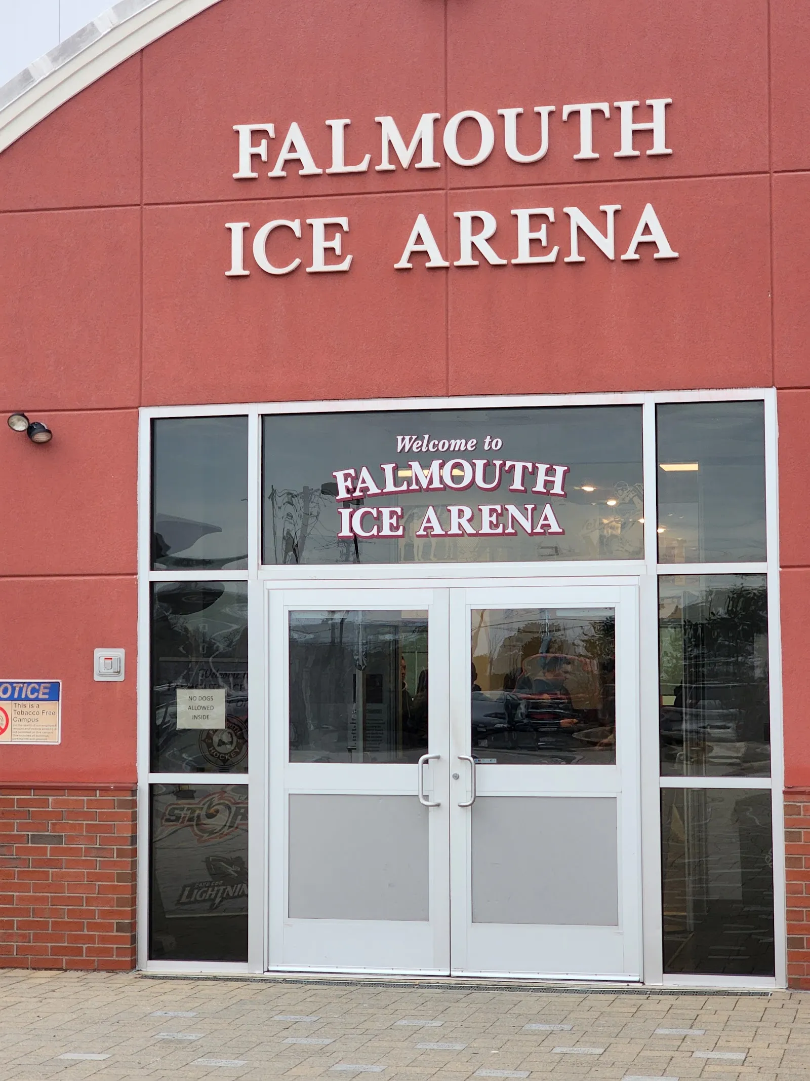 The red brick entrance of the Falmouth Ice Arena with its name in white letters above the double glass doors — Falmouth Ice Arena