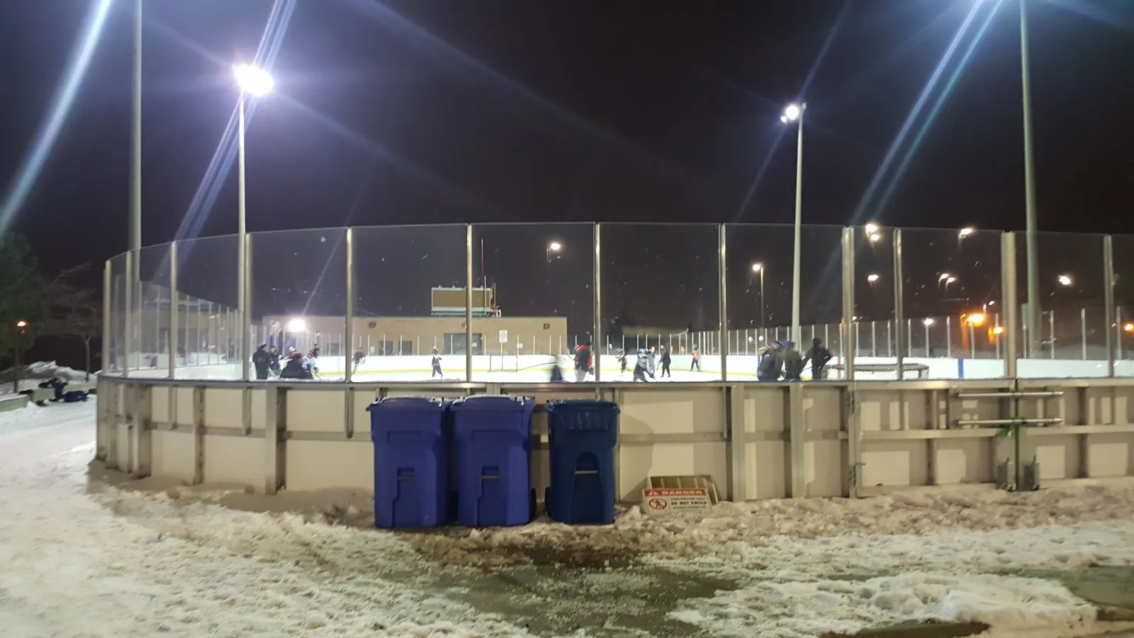 The floodlit outdoor rink at the Father Bulfon Community Centre in Vaughan at night, seen from outside the boards — Father E. Bulfon Community Centre Outdoor Rink (Vaughan)