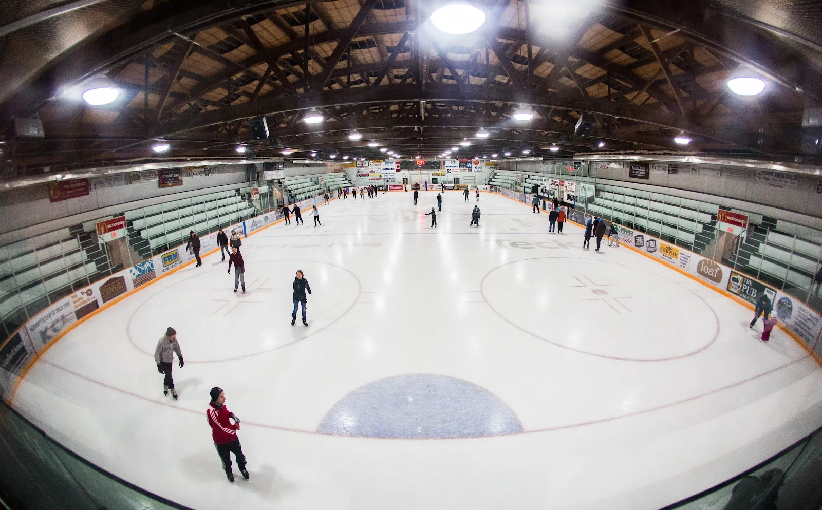 Hielo y gradas verdes del Fernie Memorial Arena durante una sesión de patinaje público, vistos desde la pista — Fernie Memorial Arena