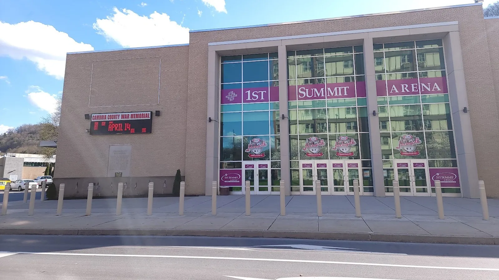 La fachada del 1st Summit Arena en Johnstown, con su nombre a lo ancho de una alta fachada de vidrio junto al letrero de Cambria County War Memorial — 1st Summit Arena