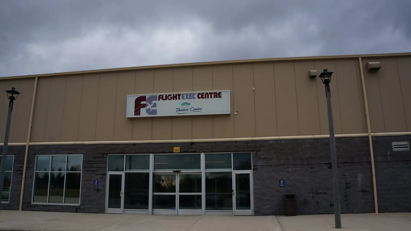 La fachada con revestimiento color canela del FlightExec Centre con su letrero sobre una entrada de vidrio. — FlightExec Centre (Dorchester)