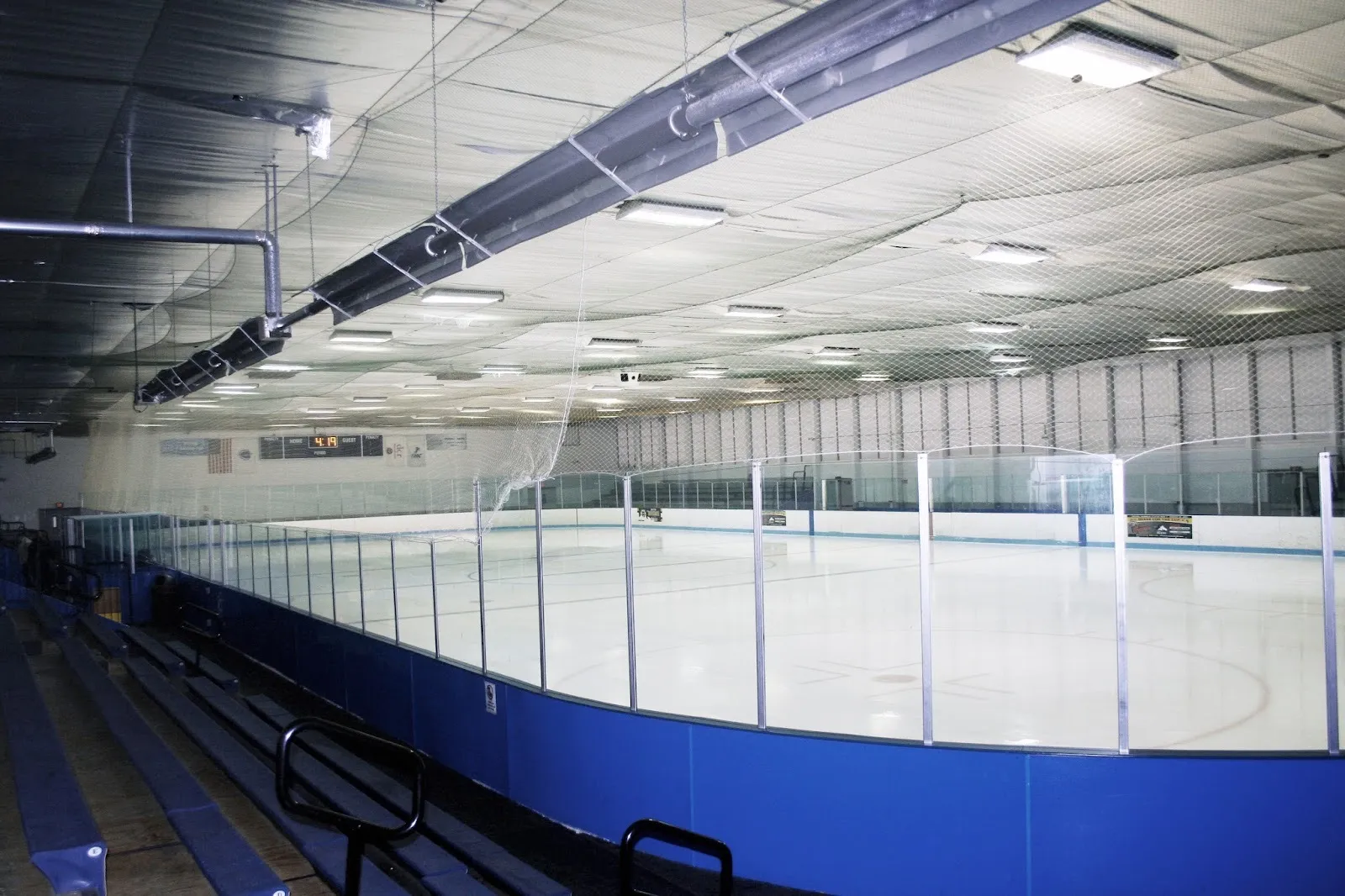 The empty ice at Asiaf Arena in Brockton, seen from the bleachers behind the blue boards and glass — Asiaf Arena