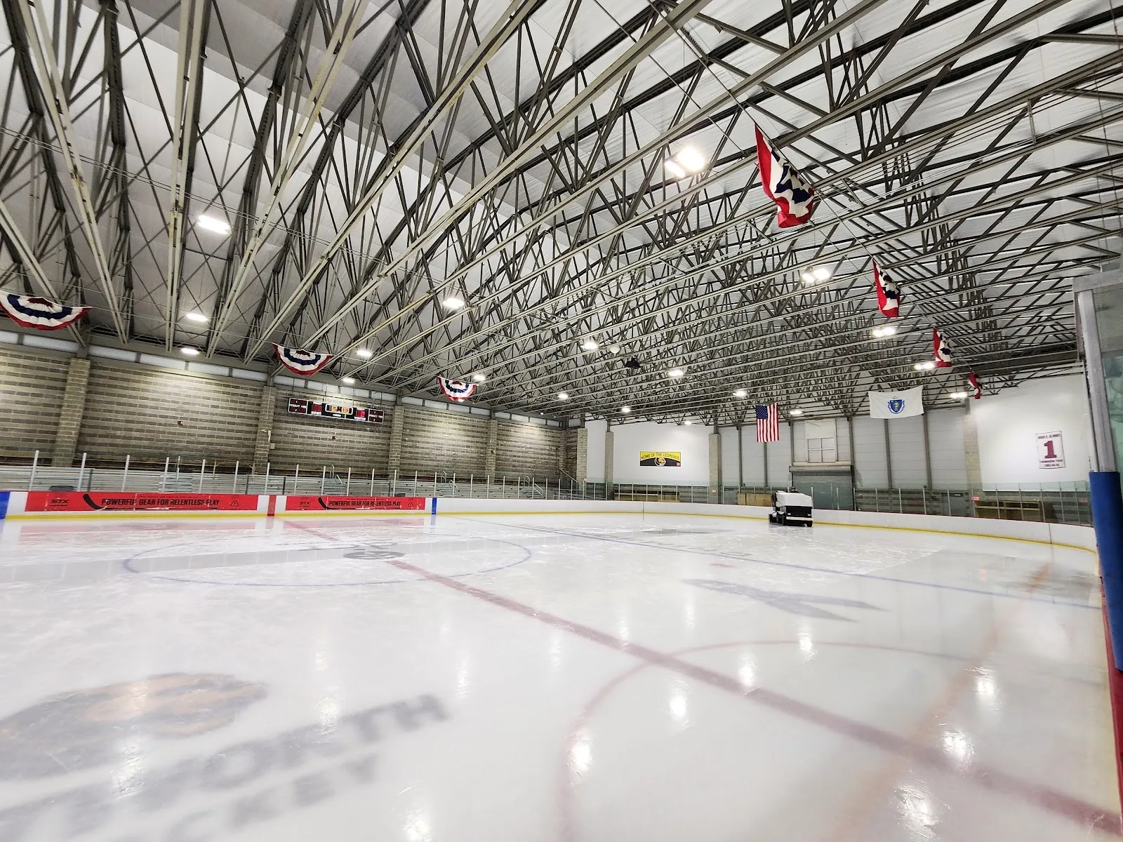 The ice at the Allied Veterans Memorial Rink in Everett from rink level, under the steel roof trusses hung with bunting and flags — Allied Veterans Memorial Rink