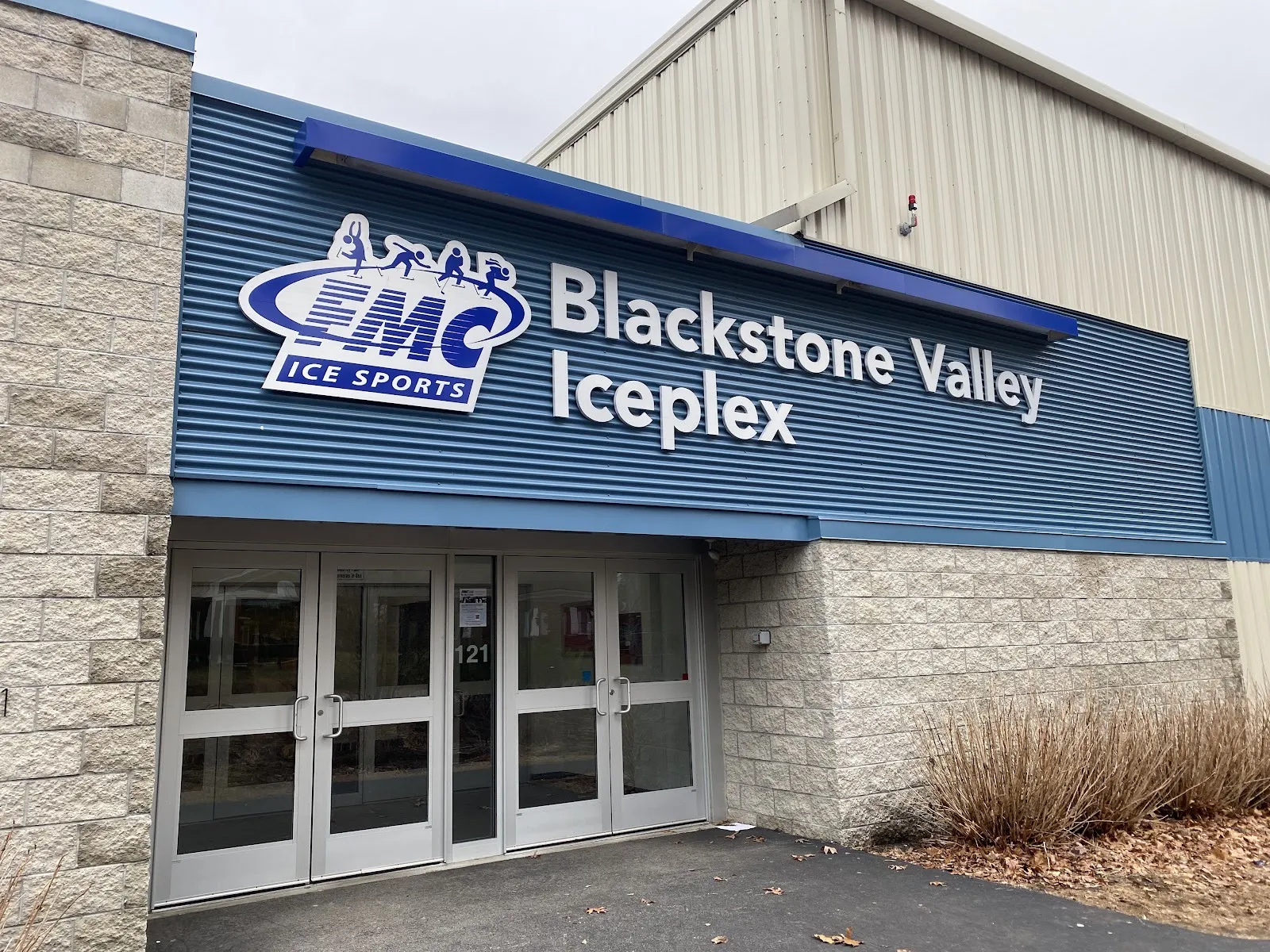 The Blackstone Valley IcePlex entrance at number 121, its name in white letters on blue cladding above glass doors — Blackstone Valley IcePlex
