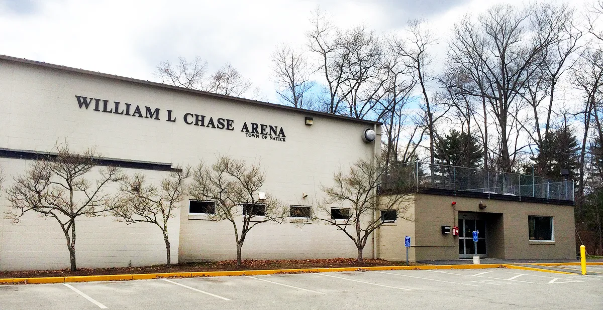 Frente de William L. Chase Arena, un edificio de ladrillo color arena con las letras "WILLIAM L CHASE ARENA / TOWN OF NATICK" en la pared y la entrada visible a la vuelta de la esquina. — William L. Chase Arena