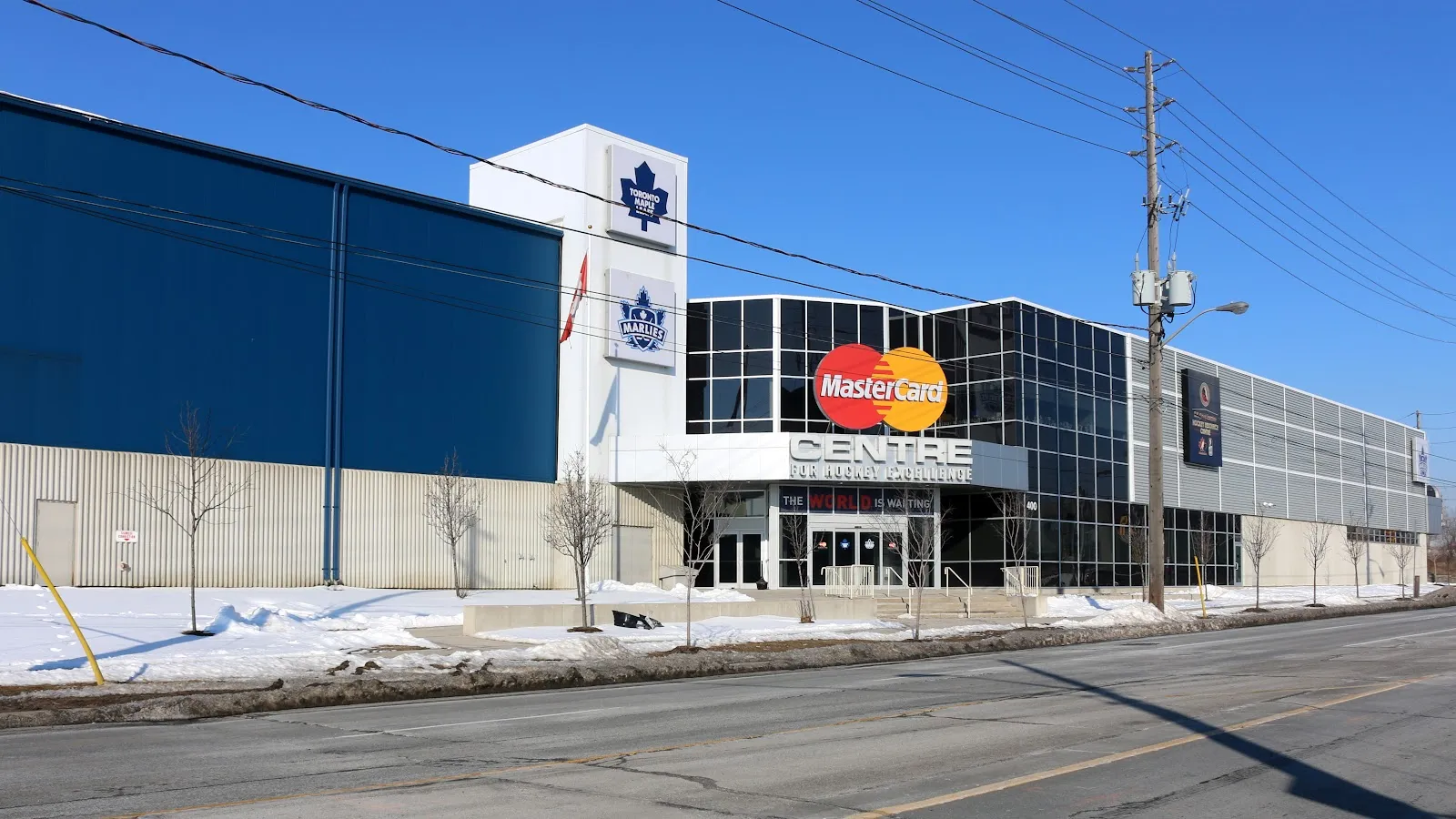 The long blue and glass facade on Kipling Avenue in winter, still carrying its earlier MasterCard Centre signage and Maple Leafs logos. — Ford Performance Centre