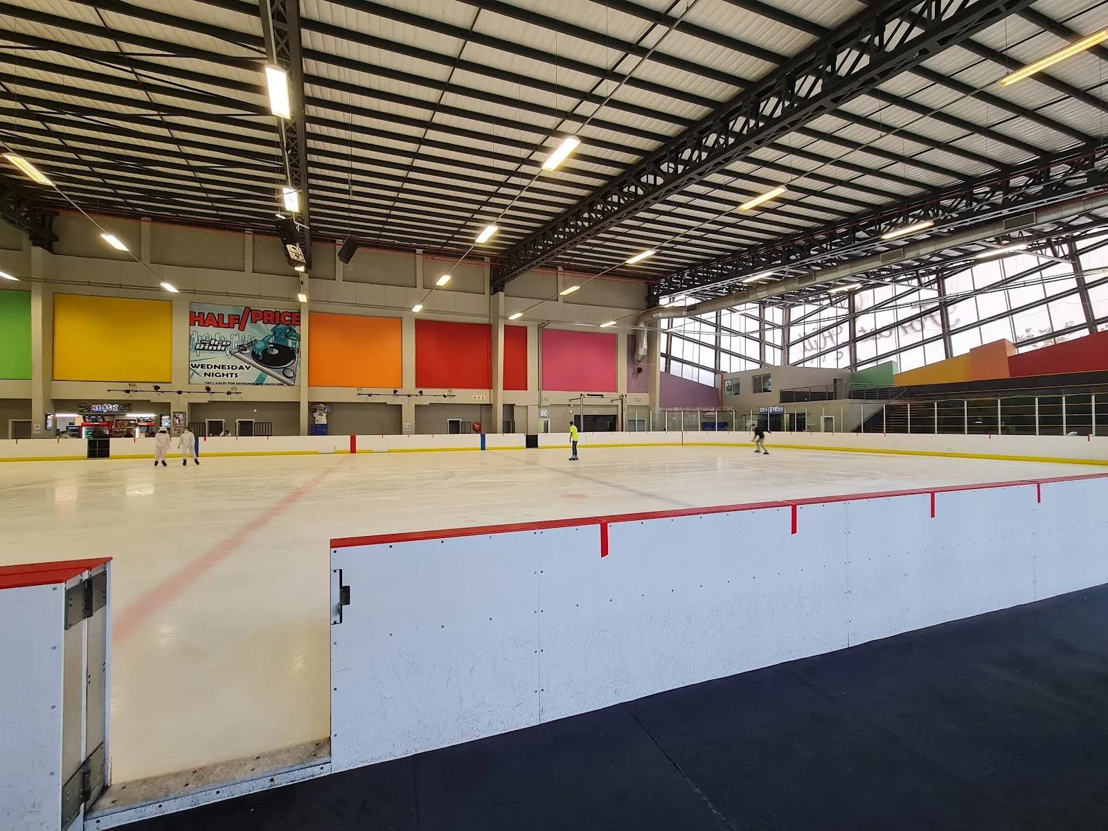 The empty ice sheet and boards of the Forest Hill Ice Rink under the lit roof — Forest Hill Ice Rink