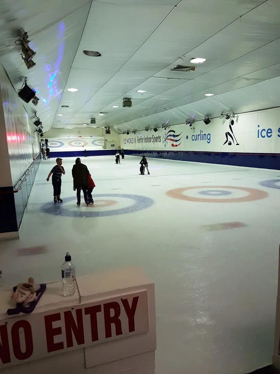The long ice hall with curling rings painted under the ice and a few skaters on it, the end wall lettered 'Ice World & Forfar Indoor Sports - curling - ice skating'. — Forfar Indoor Sports (Ice World)