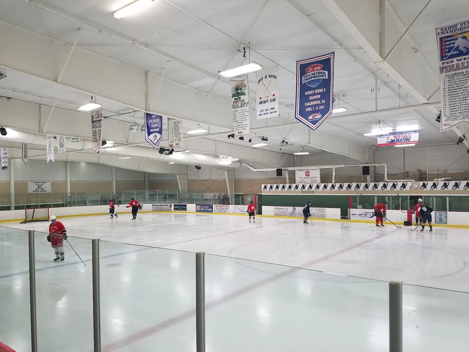 Hockey practice on the ice sheet at Fort Myers Skatium, players at the far side under the banners — Fort Myers Skatium