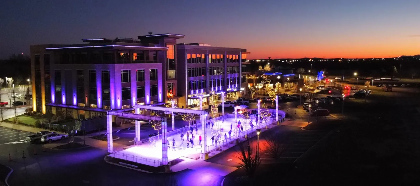 Fountains Winterfest rink lit up at dusk beside the Fountains at Gateway offices — Fountains Winterfest Ice Rink