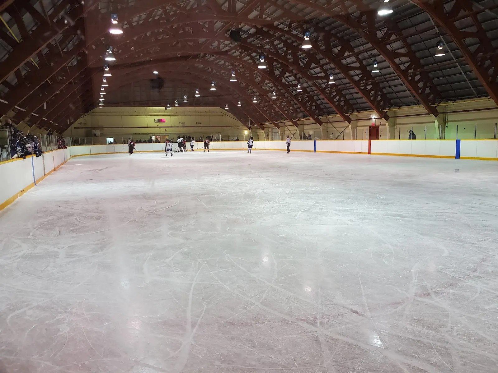 La amplia pista de Frank Doherty Arena en Thorold bajo su techo de madera en arco, con unos cuantos jugadores al fondo de la pista — Frank Doherty Arena