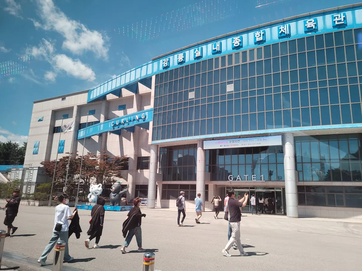 The glass-fronted entrance of the Gangneung Indoor Gymnasium building, Gate 1, with its Hangul sign across the top. — Gangneung Indoor Ice Rink