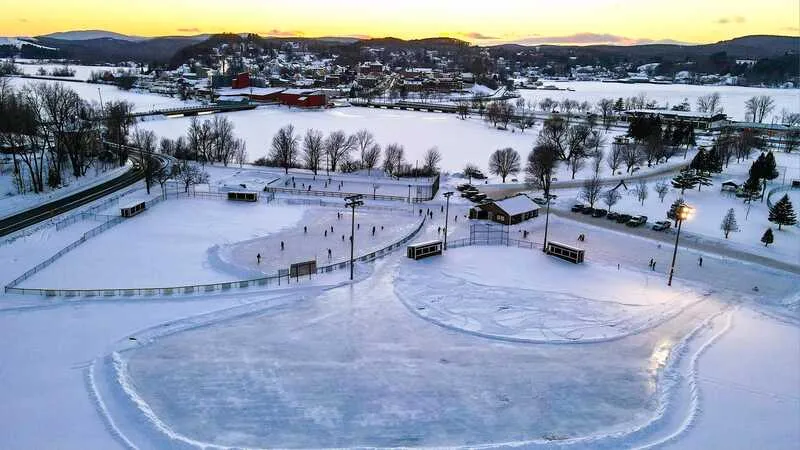 Aerial view of the Gardner Park rinks in Newport at dusk, with the skating rinks marked out on the snow-covered park and the town behind. — Gardner Park Ice Rinks