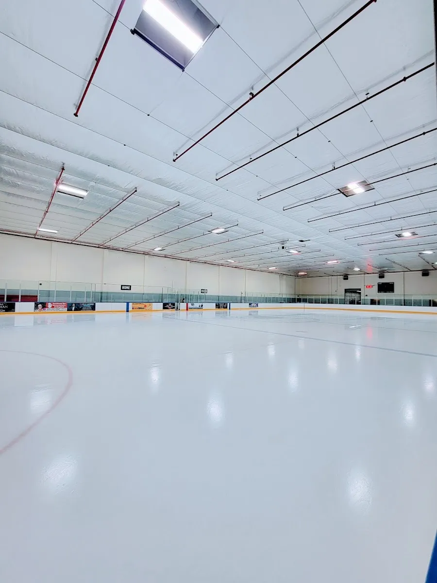 The empty, freshly flooded ice sheet under a white insulated ceiling with rows of lights. — Garnet A. Williams Community Centre (Vaughan)