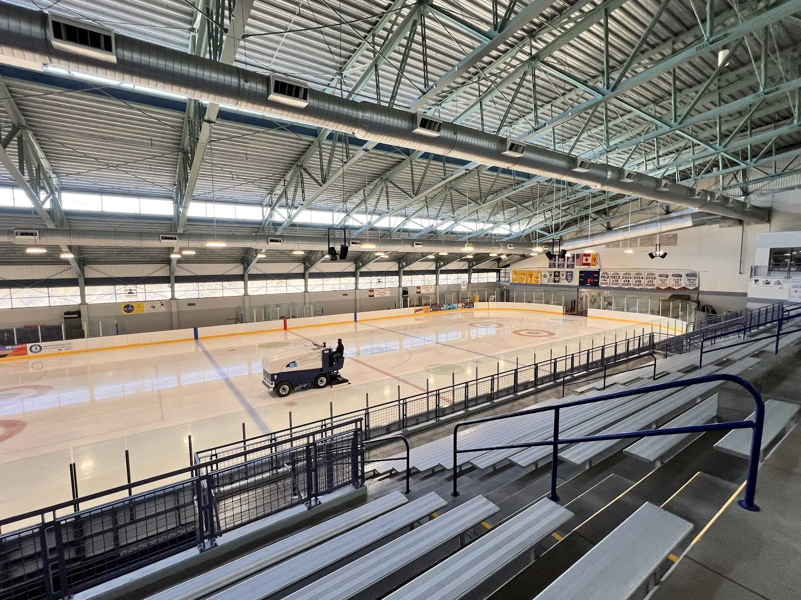 La pista de hielo del Genoveva Chavez Community Center, con una máquina alisadora sobre el hielo y las gradas a lo largo de un lado. — Genoveva Chavez Community Center