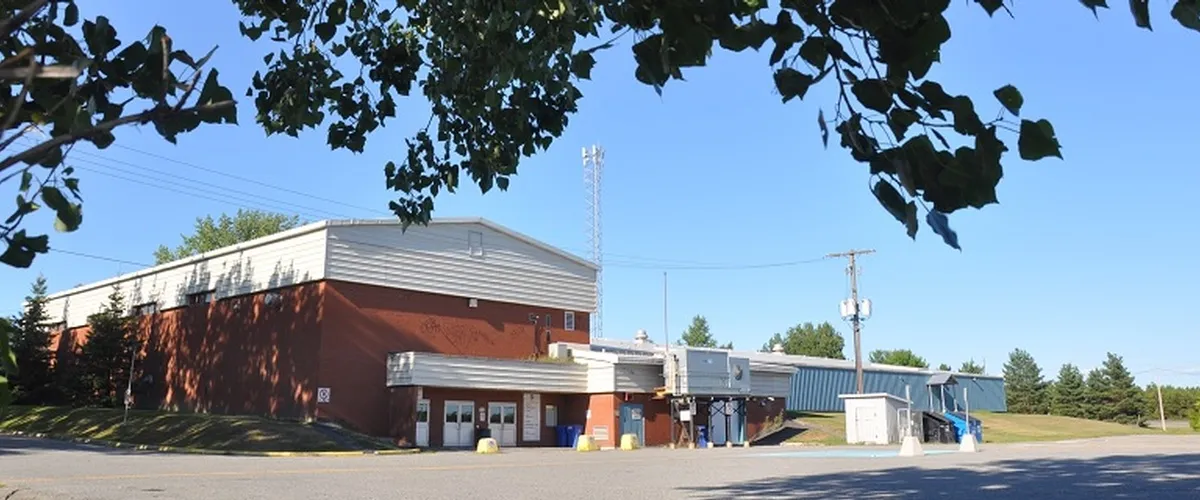 The long brick and metal arena building with its entrance canopy, seen from the parking lot. — George Armstrong Community Centre and Arena (Garson)