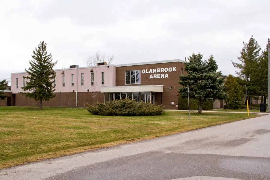 The Glanbrook Arena, its name in white letters on a brick block above a glass entrance canopy, lawn and evergreens in front. — Glanbrook Arena