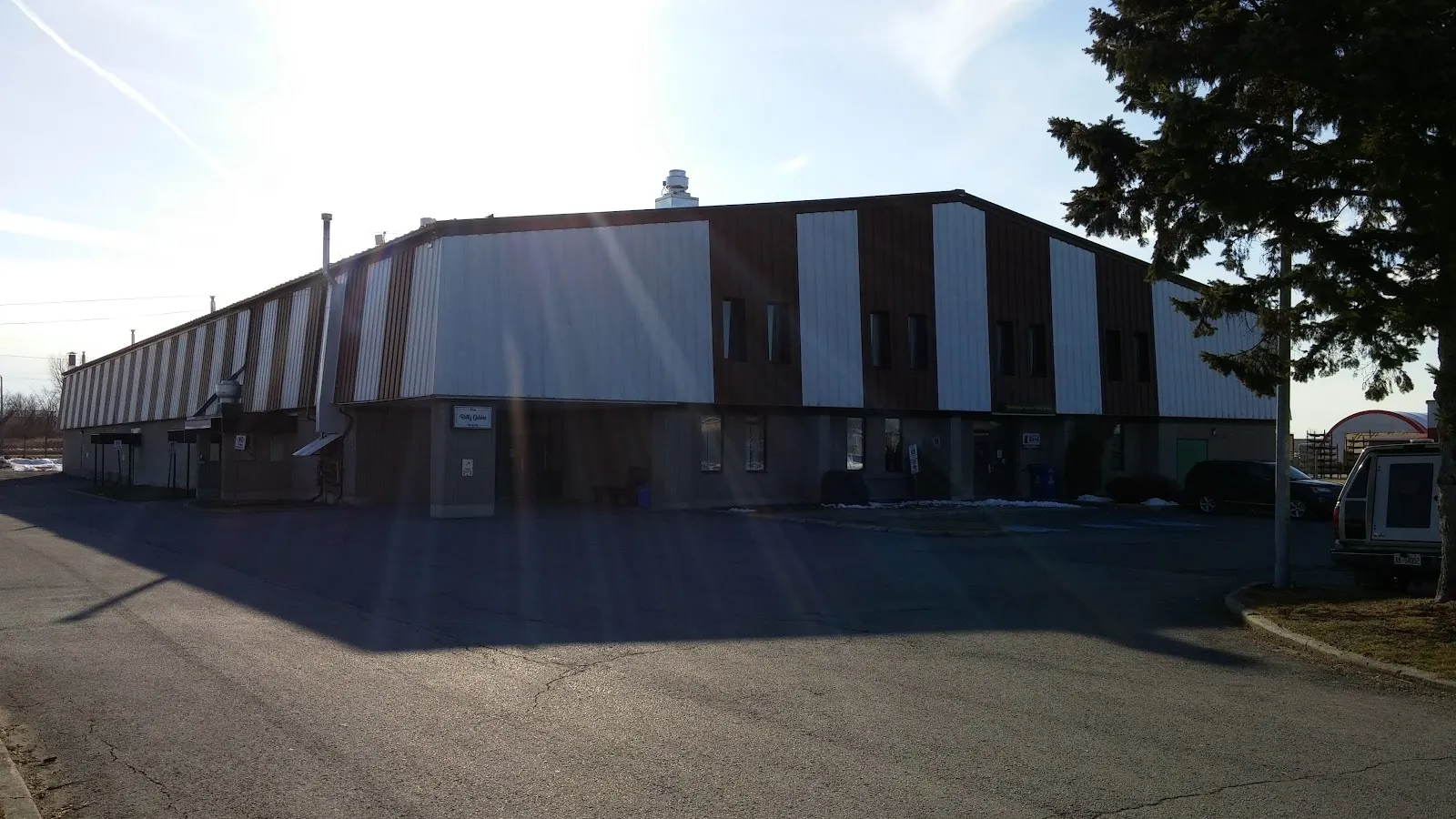 The long brown-and-white striped Glengarry Sports Palace in Alexandria, seen across its parking lot. — Glengarry Sports Palace (Alexandria)