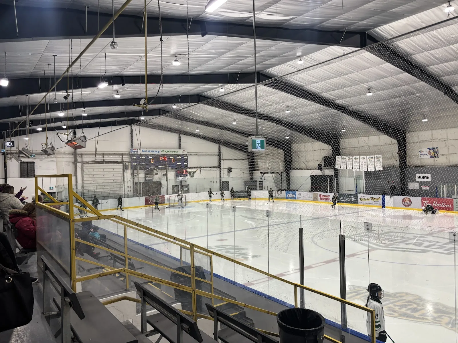 The Billy Gebbie Arena ice inside the Glengarry Sports Palace, seen from the stands under a dark steel roof. — Glengarry Sports Palace (Alexandria)