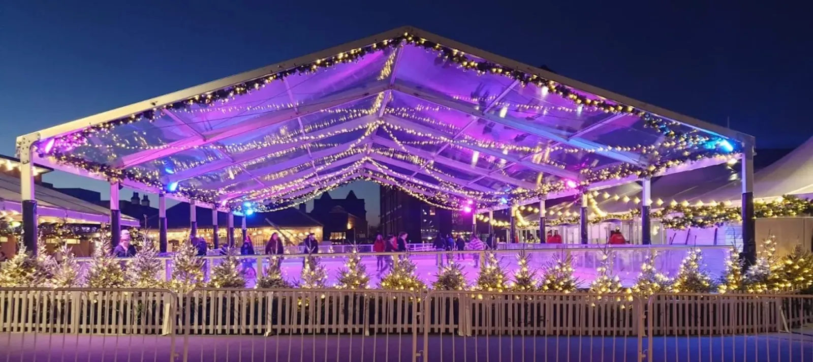 The canopy-covered Gloucester Quays Christmas Ice Rink at night, with skaters on the ice — Gloucester Quays Christmas Ice Rink