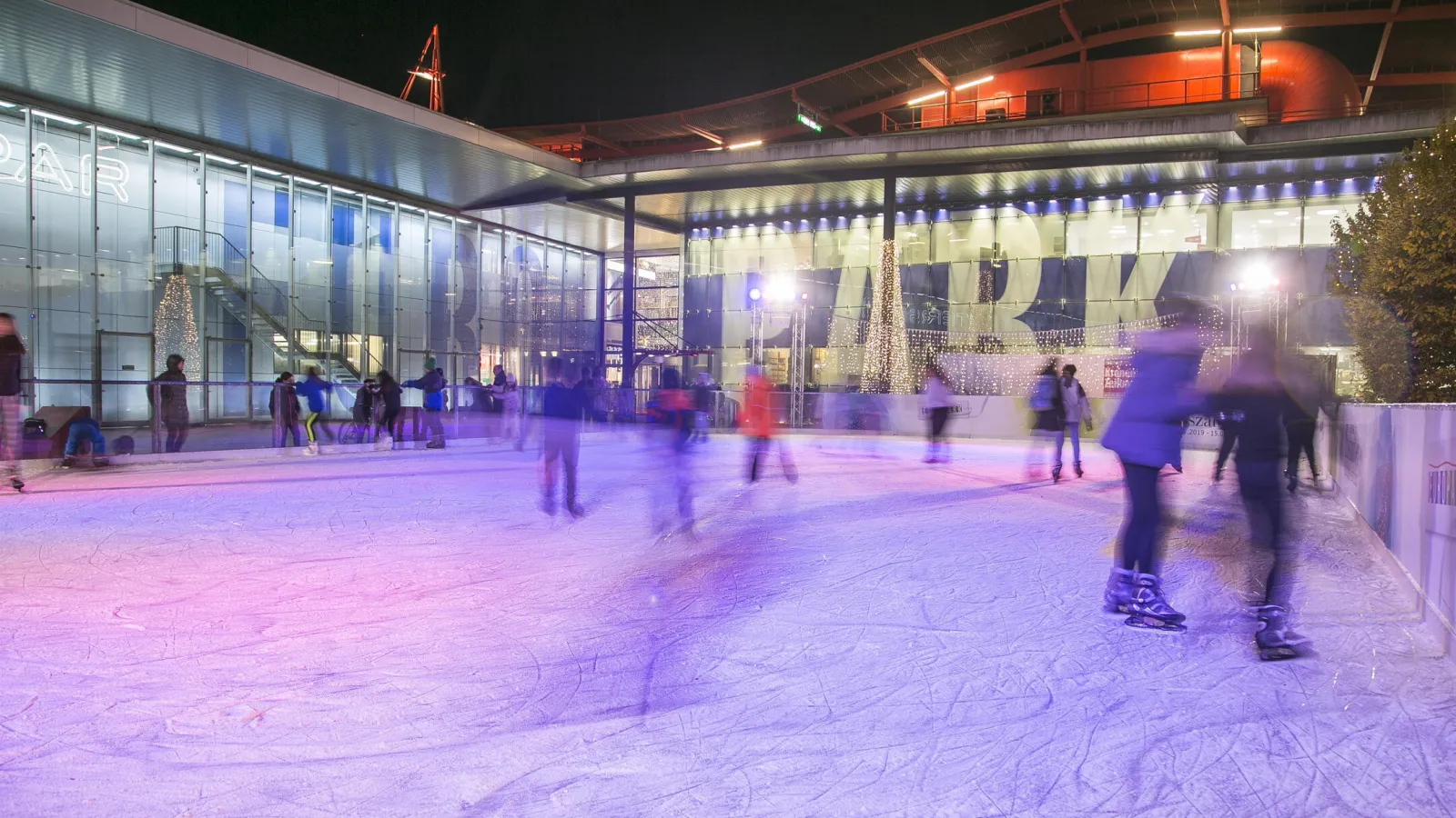 The Europark rink at night, skaters on the lit ice in front of the glass shopping-centre front with its large EUROPARK lettering. — Gratis-Eislaufplatz Europark