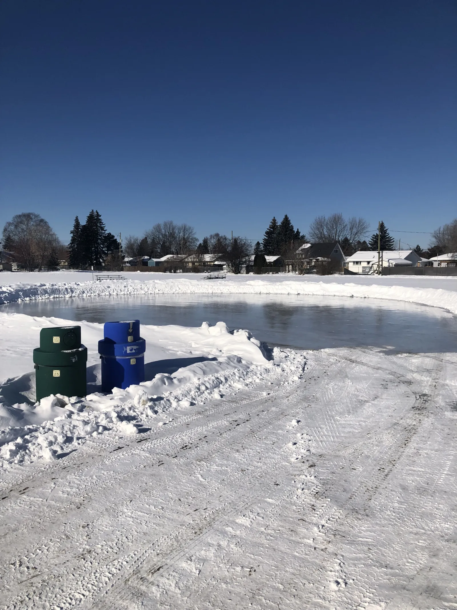 El estanque de patinaje de Green Acres Park con botes de basura junto al sendero despejado — Green Acres Park Skating Pond