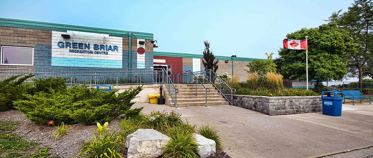 The Greenbriar Recreation Centre entrance, steps and railings rising to a tiled wall lettered Green Briar Recreation Centre beside a flagpole. — Greenbriar Recreation Centre