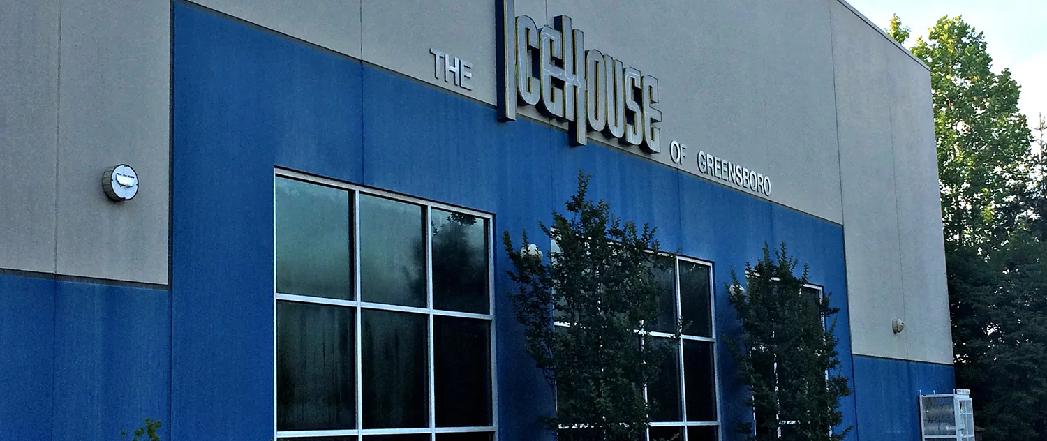 Corner of the rink building under a bright sky — The Greensboro Ice House