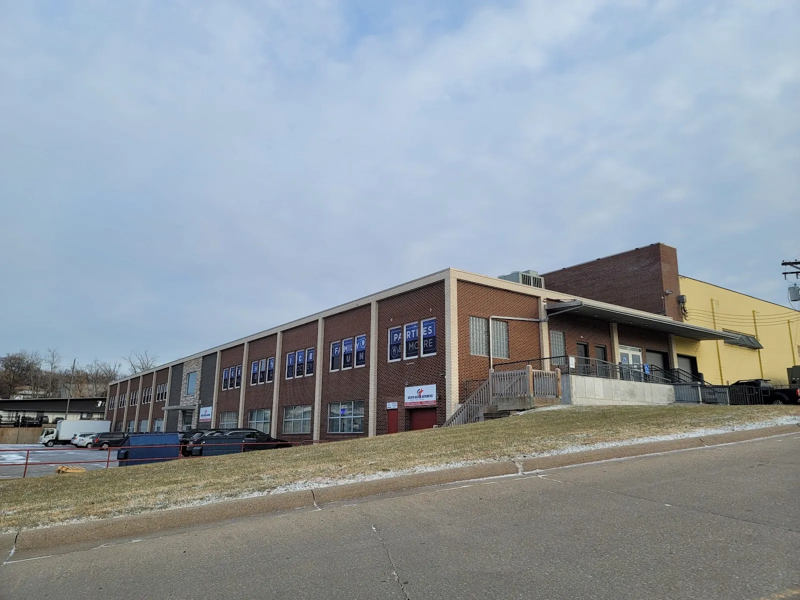 The long brick Grover Street building, its upper windows lettered Ice Skating, Broomball, Ice Hockey and Parties, with a yellow hall behind. — Grover Ice