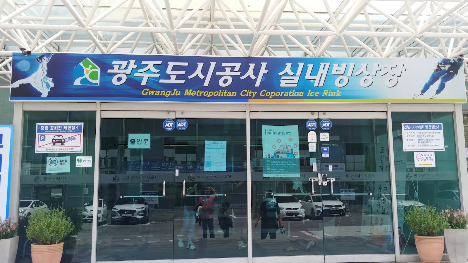공사 표지판 아래 광주 실내빙상장의 유리 출입문. 표지판은 한국어와 영어로 되어 있어요. — Gwangju Indoor Ice Rink