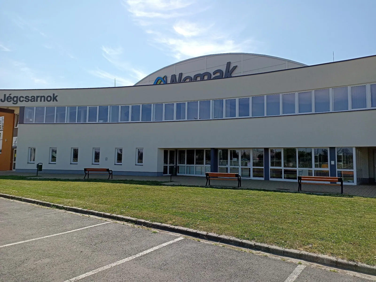 The front of the Győri Egyetemi Jégsport Központ ice hall in Kiskútliget, with its parking lot and lawn — Győri Egyetemi Jégsport Központ