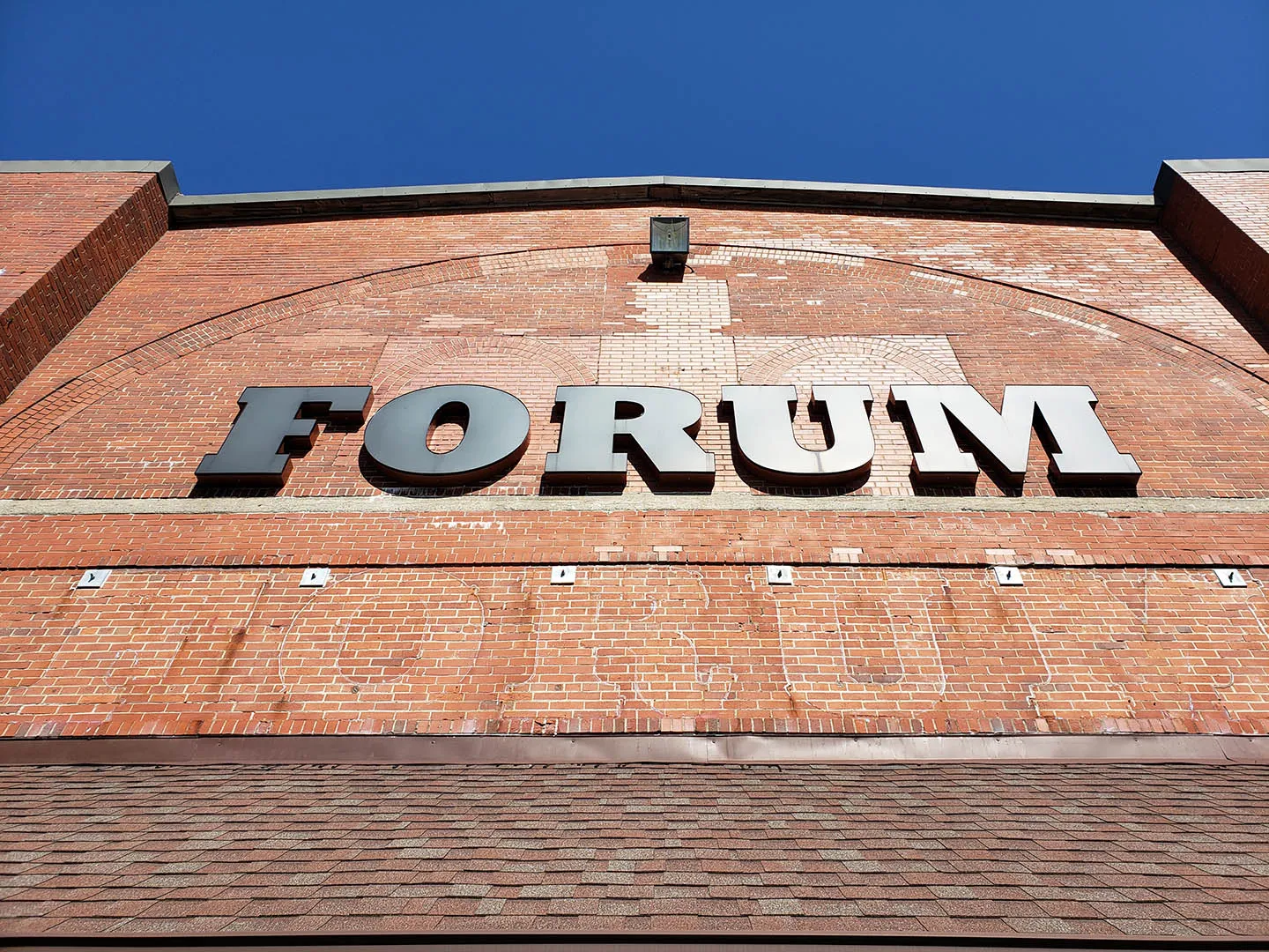 Low-angle view of the Halifax Forum's brick facade with the raised metal FORUM signage above the entrance. — Halifax Forum